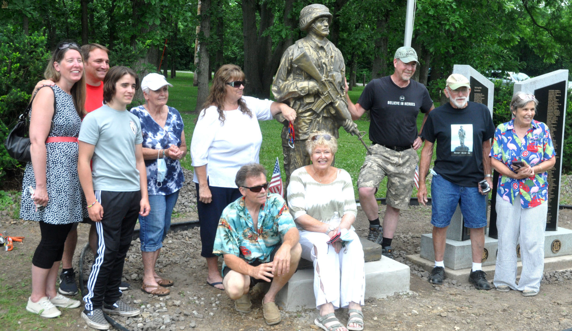A group of Bloomfield residents gather around a military statue that was installed in the community